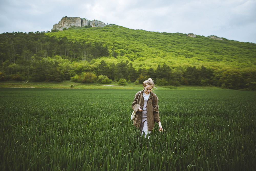 Woman wearing jacket walking in field in Crimea, Ukraine