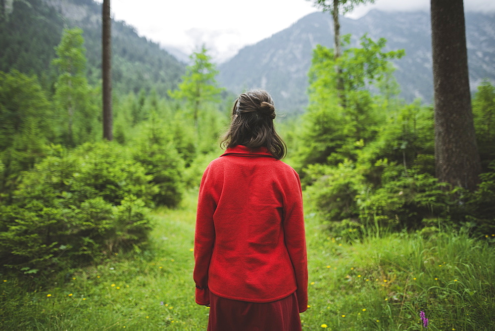 Young woman with red jacket in forest