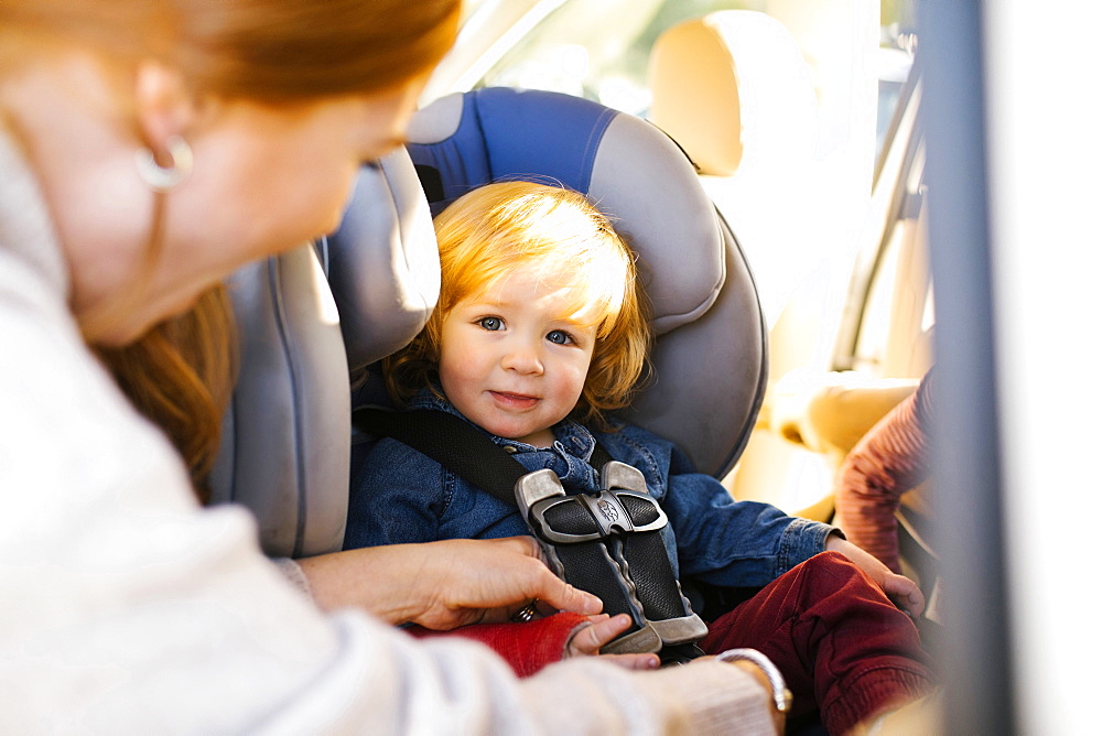 Boy having his seat belt buckled by his mother