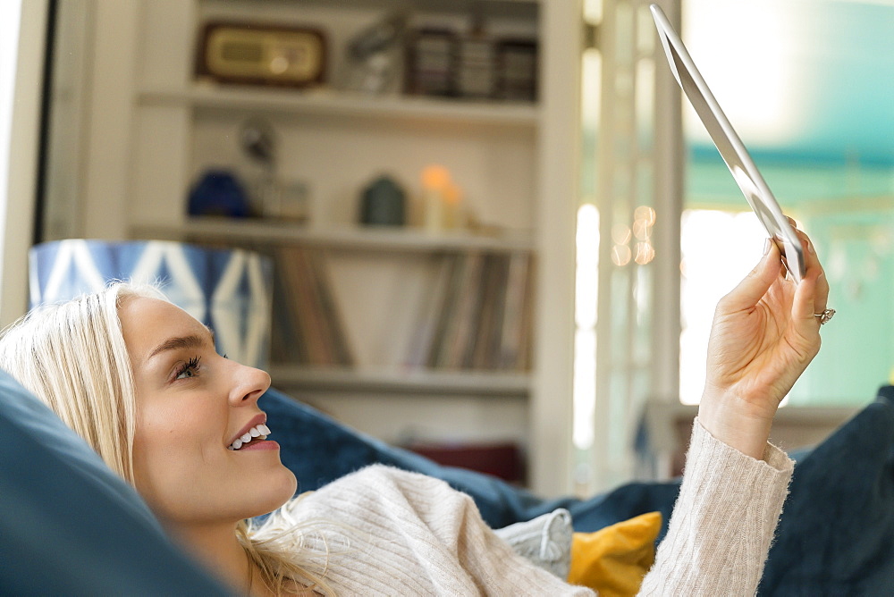 Woman using tablet while lying on sofa