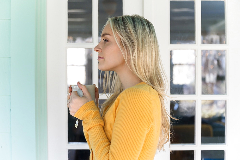 Portrait of woman in yellow sweater holding mug