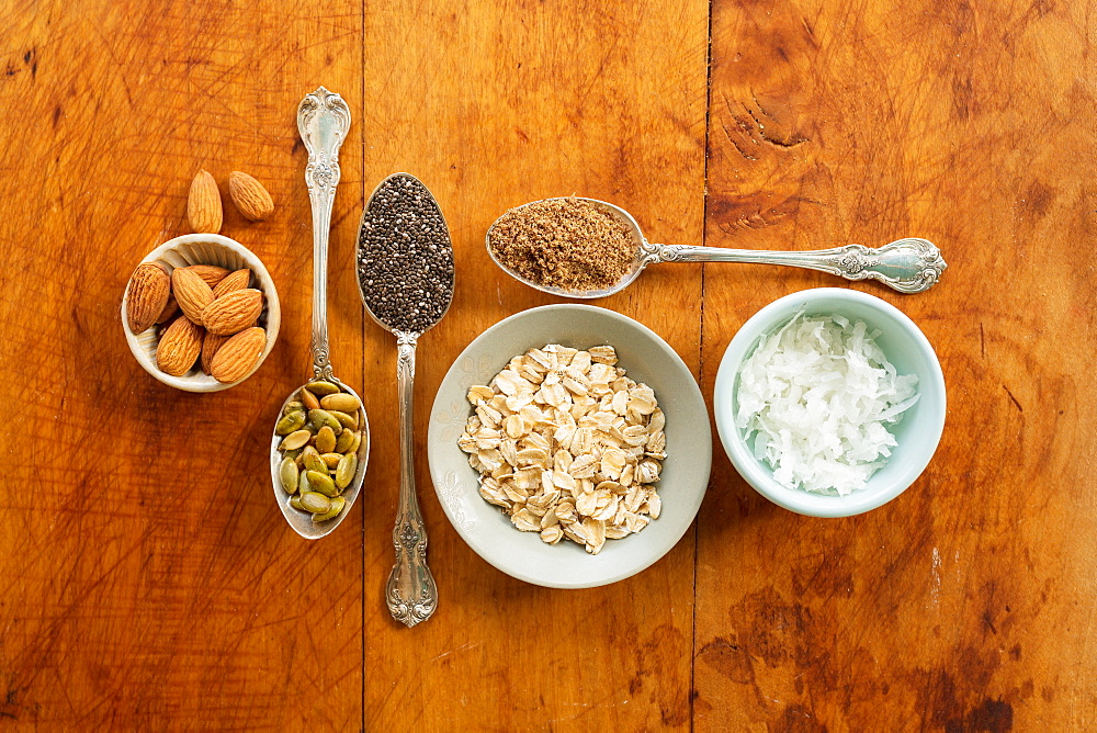 Oats, nuts, seeds flax and coconut flakes against wood