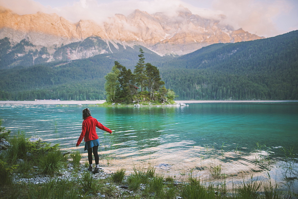 Germany, Bavaria, Eibsee, Young woman walking at shore of Eibsee lake in Bavarian Alps