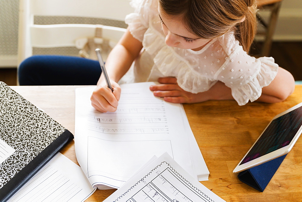 Girl (6-7) working on schoolwork at home