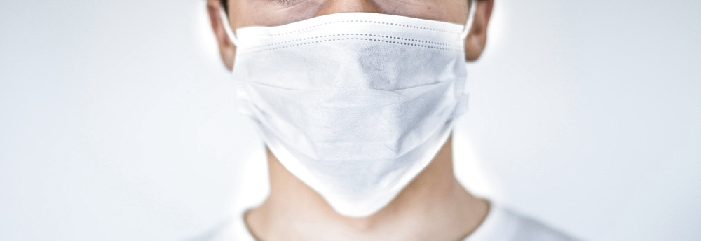 Studio shot of teenage boy (16-17) wearing protective mask