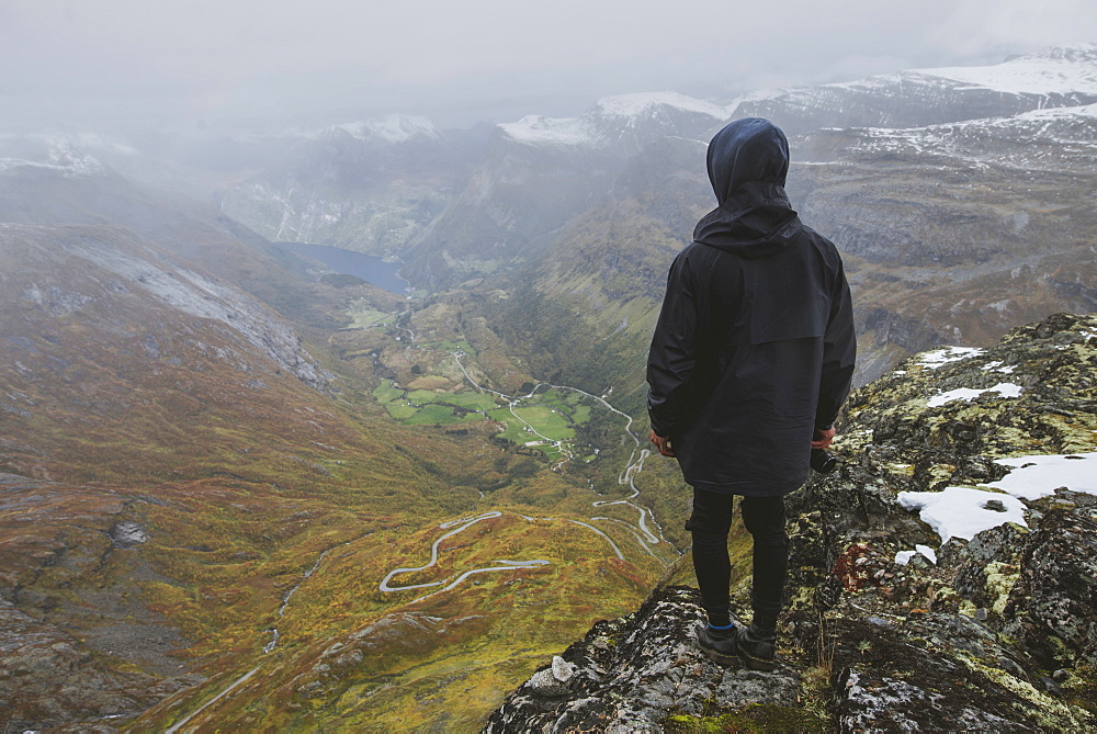 Man holding camera on Dalsnibba mountain overlooking valley in Geiranger, Norway