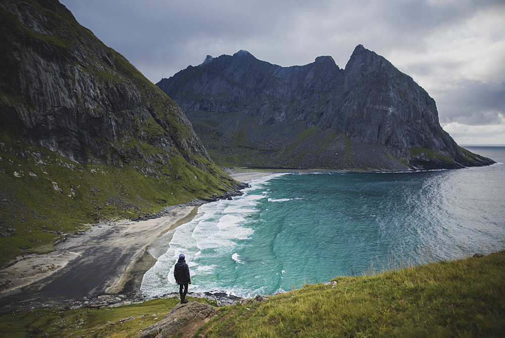 Man standing on rock by Kvalvika Beach in Lofoten Islands, Norway