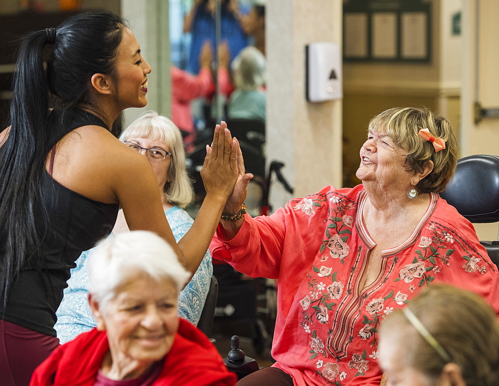 Smiling fitness instructor high-fiving smiling senior woman