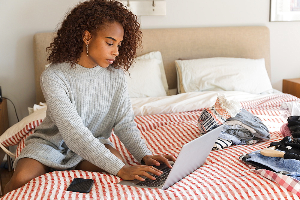 Woman using laptop on bed