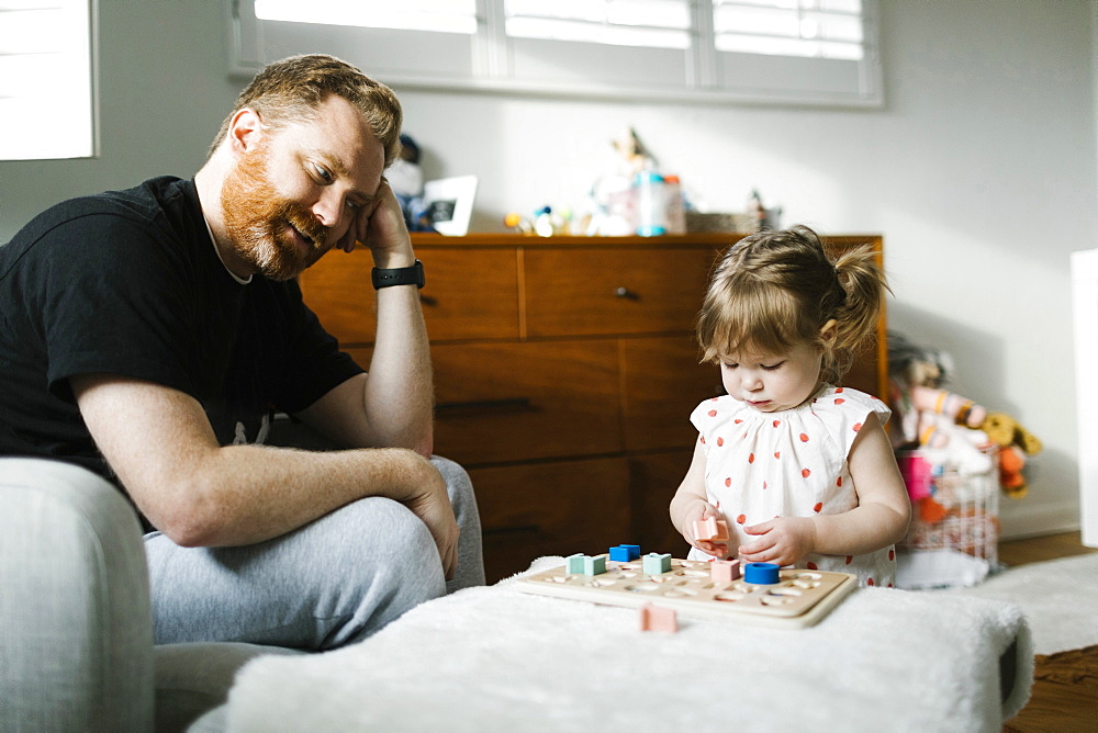 Father watching daughter (2-3) play 