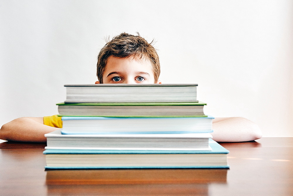 Boy behind stack of books