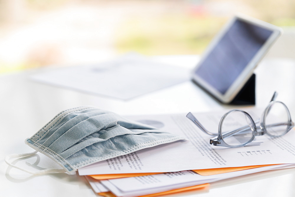 Face mask on business papers and tablet