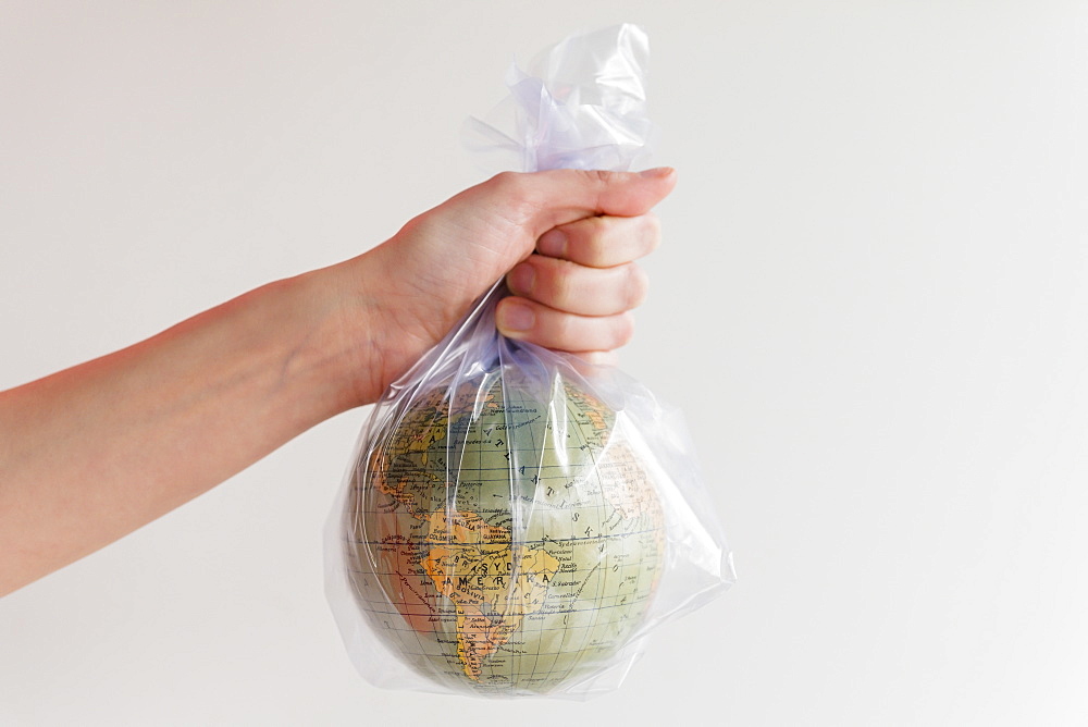 Hand holding earth globe in plastic bag