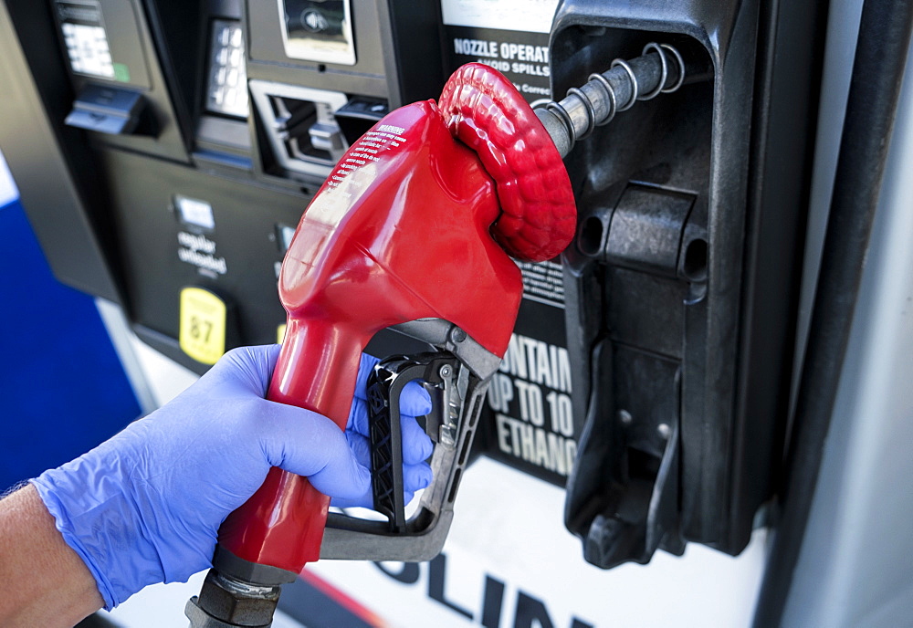 Gloved hand holding gas station nozzle