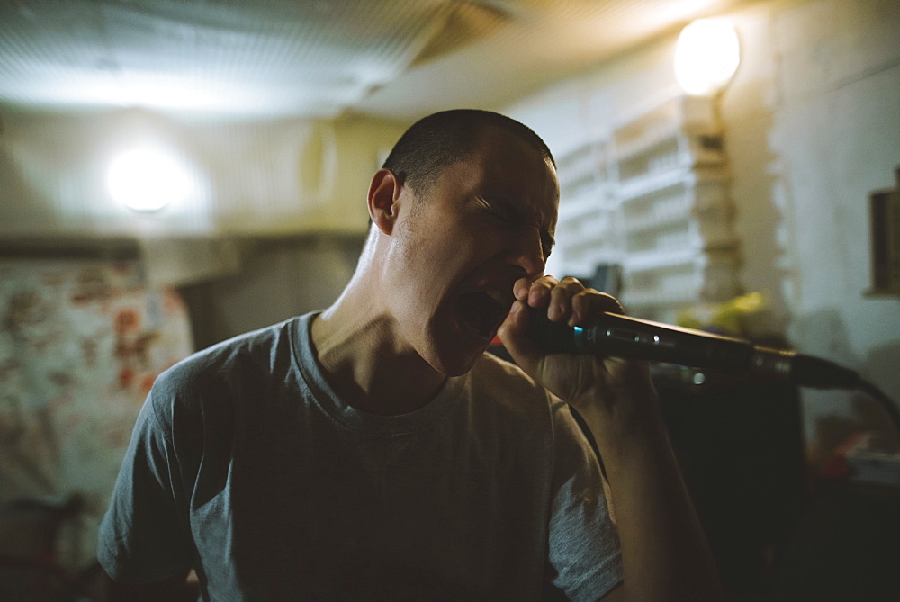 Young man singing during rehearsal in garage