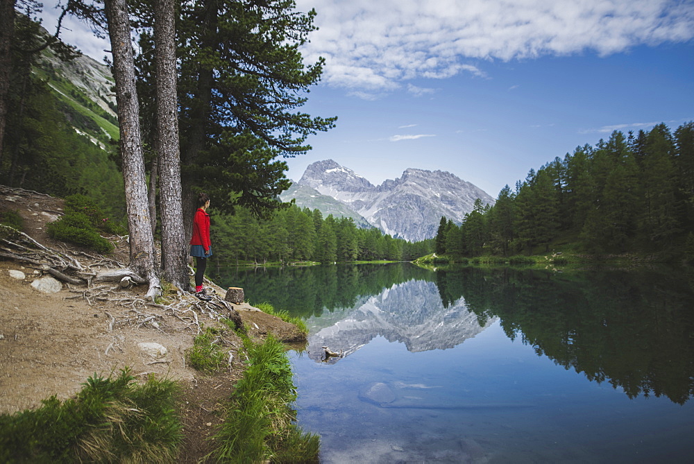 Switzerland, Bravuogn, Palpuognasee, Young woman resting on bench near Palpuognasee lake in Swiss Alps