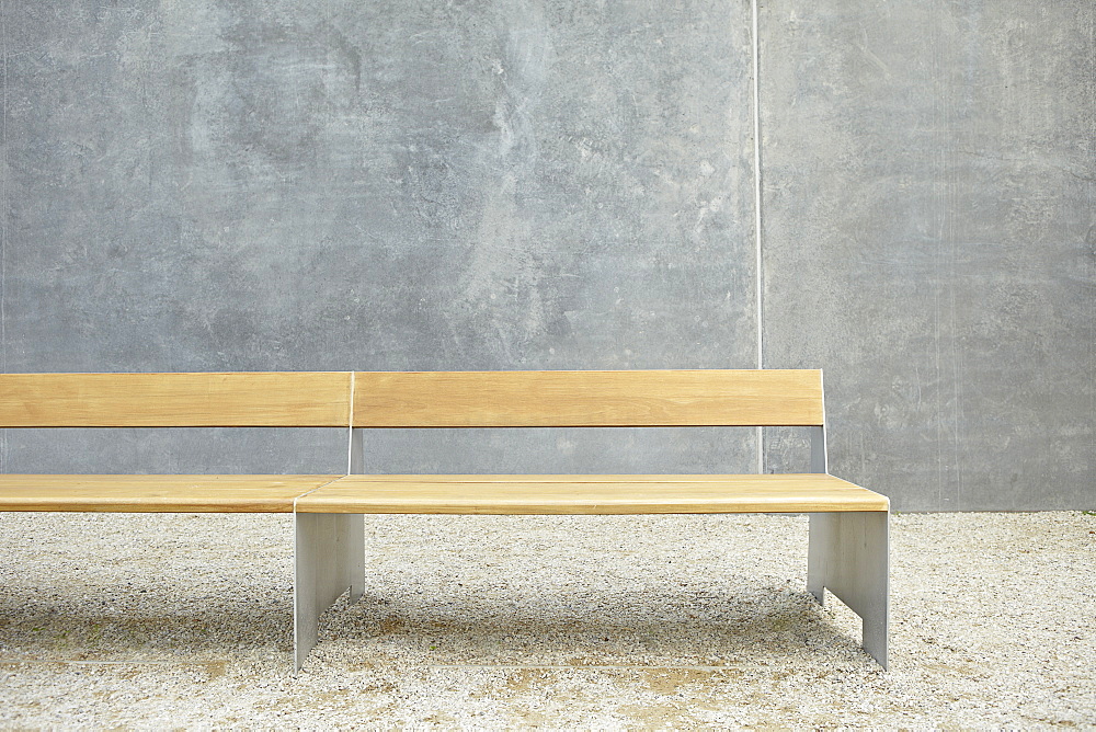 Wooden modern bench against concrete wall