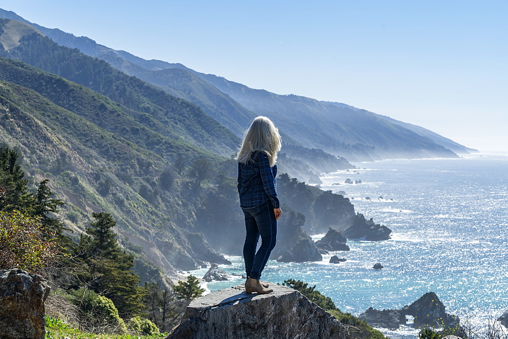 USA, California, Big Sur, Woman standing at the edge of cliff looking at view