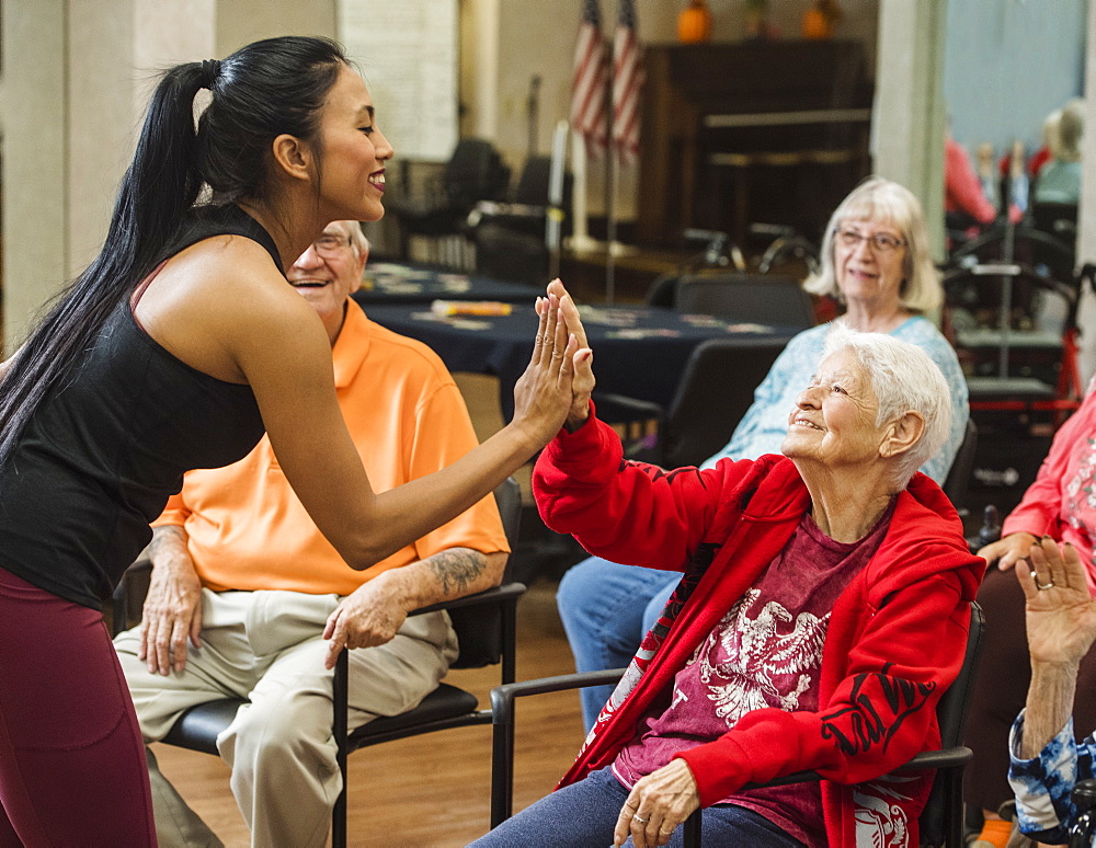 Senior woman high-fiving fitness instructor