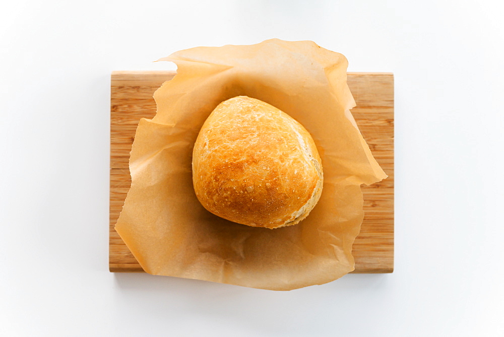 Fresh loaf of bread cooling on cutting board