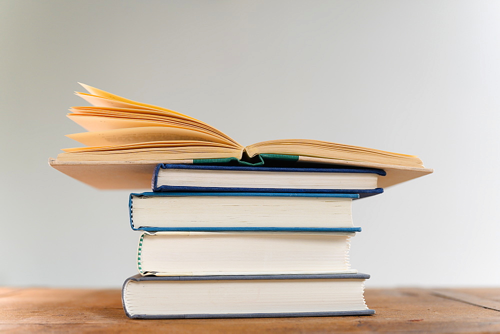 Open book on top of stack of books on desk