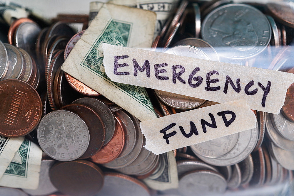 Close-up of coins and banknotes in jar labeled Emergency Found