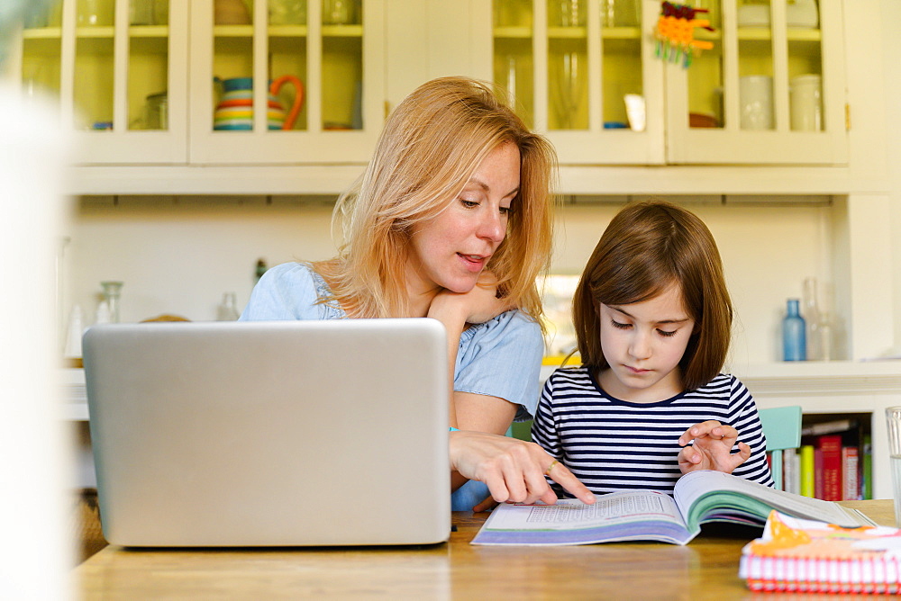 Mother helping daughter (6-7) doing homework