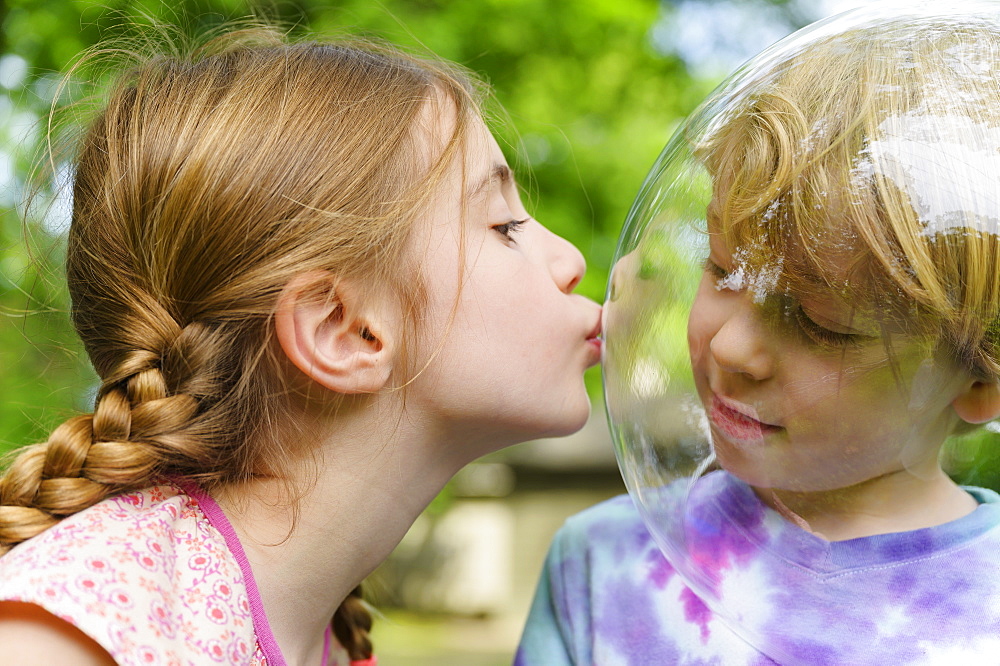 Girl kissing boy wearing bubble to socially distance