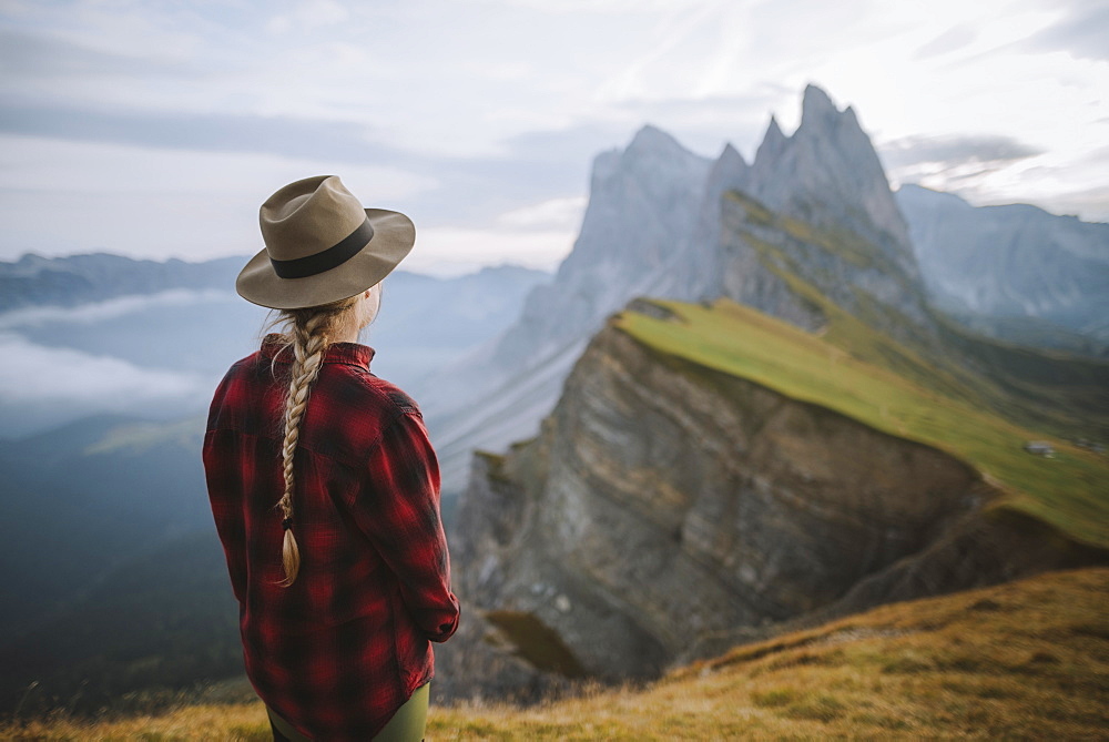 Italy, Dolomite Alps, Seceda mountain, Woman looking at scenic view of Seceda mountain in Dolomites at sunrise