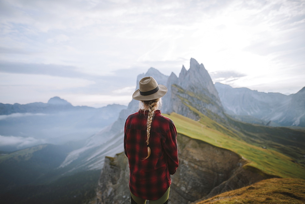 Italy, Dolomite Alps, Seceda mountain, Woman looking at scenic view of Seceda mountain in Dolomites at sunrise