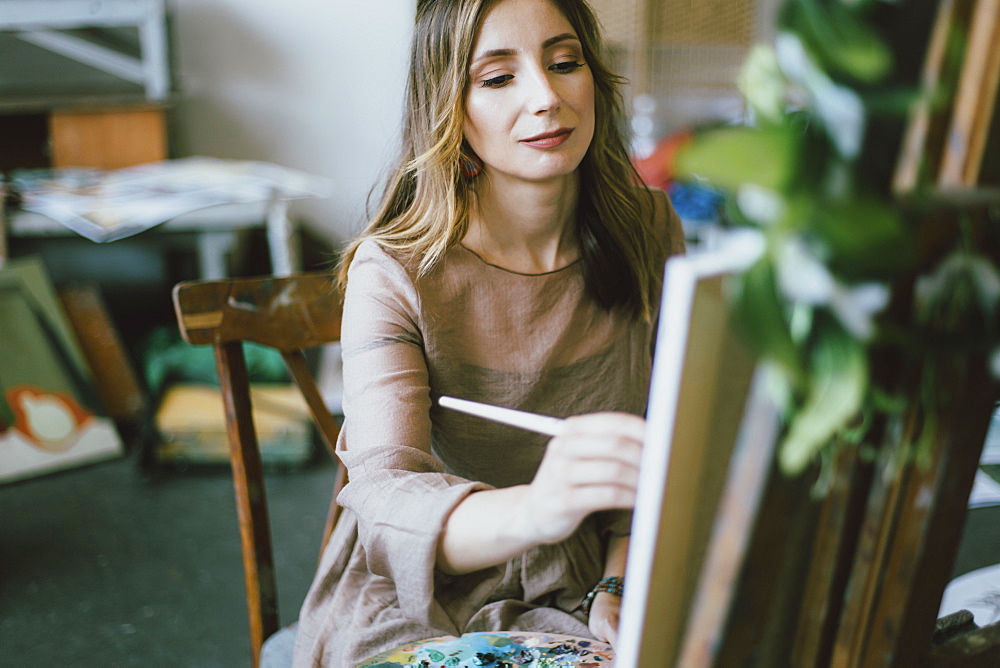 Woman painting on canvas in art studio