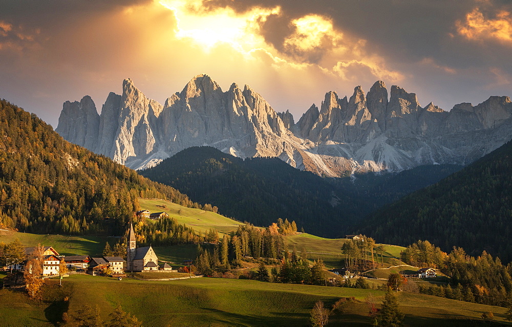 Italy, Santa Maddalena, Val di Funes (Funes Valley), Trentino-Alto Adige Region, Mountain range overlooking green valley at sunset