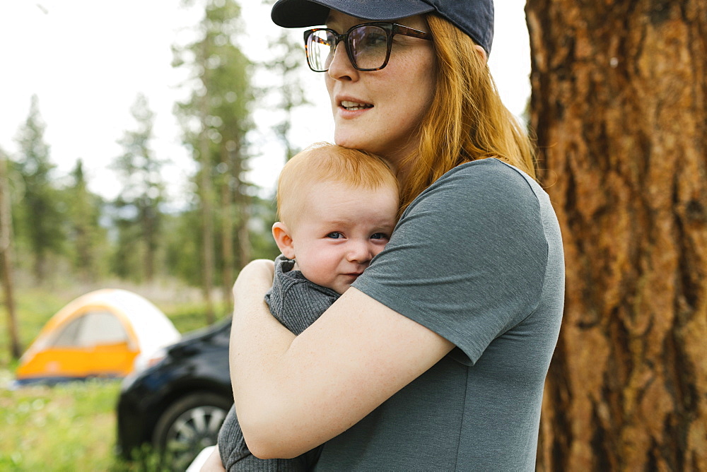 USA, Utah, Uninta Wasatch Cache National Forest, Woman holding baby son (6-11 months) during camping