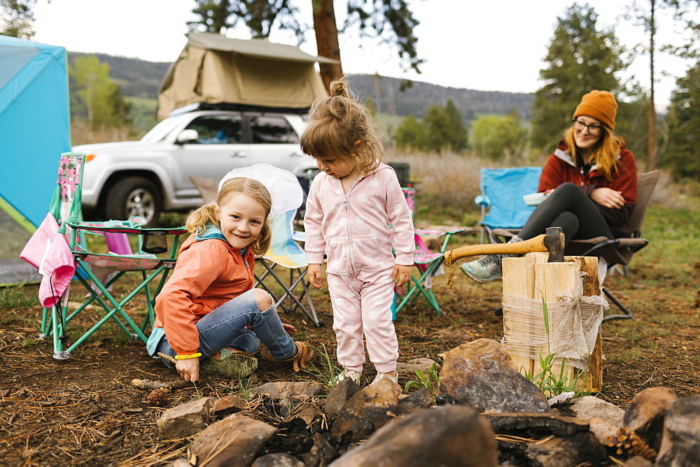 USA, Utah, Uninta Wasatch Cache National Forest, Mother looking at daughters (2-3, 6-7) playing on campsite