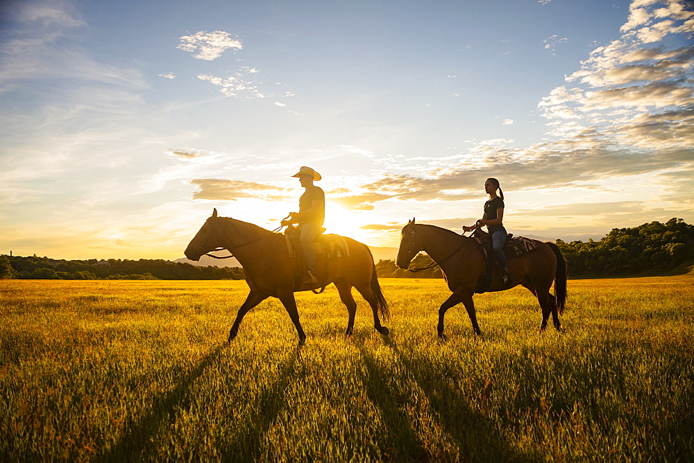 USA, Utah, Salem, Father and daughter (14-15) riding horses at sunset