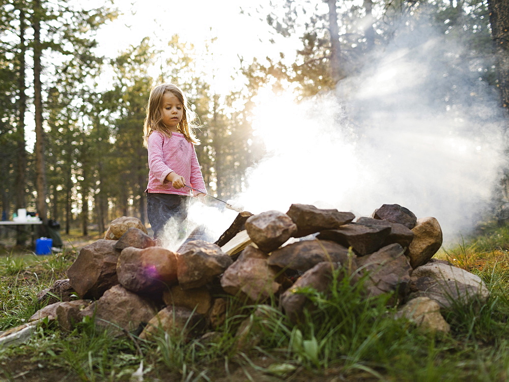 Girl (4-5) roasting marshmallow above campfire, Wasatch Cache National Forest