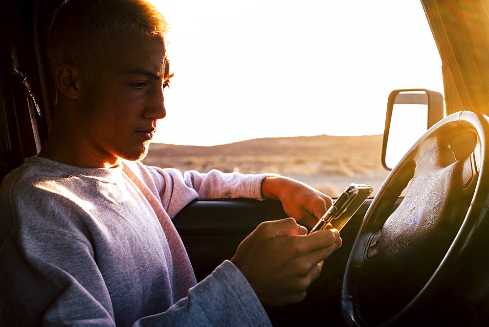 Teenager (16-17) in car using smartphone