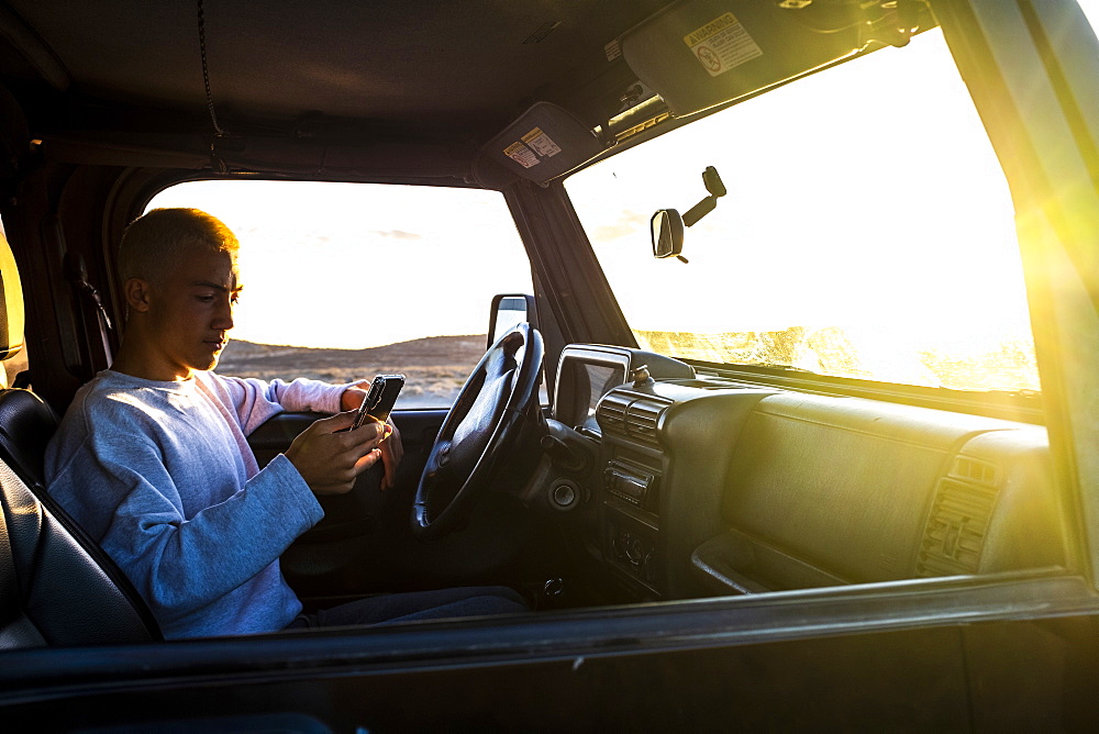 Teenager (16-17) in car using smartphone