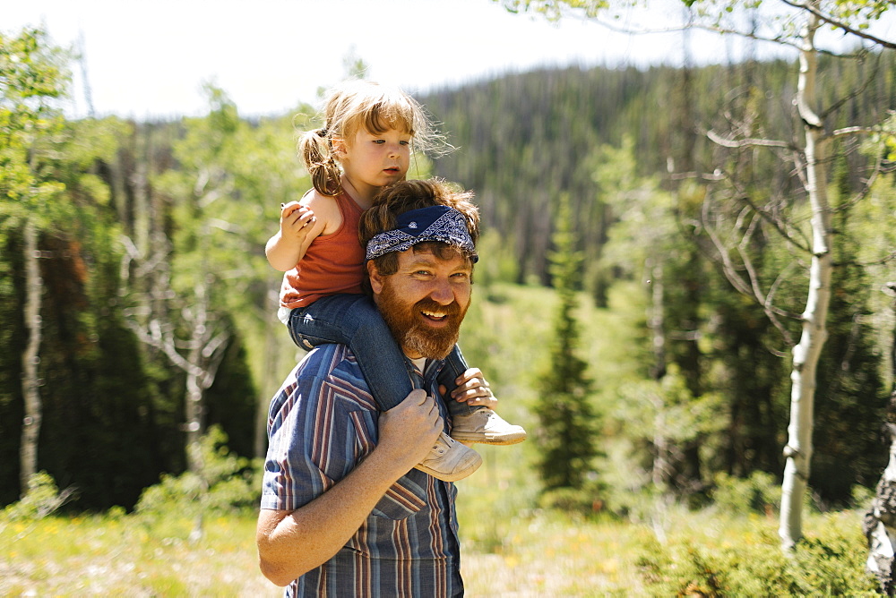 USA, Utah, Uinta National Park, Portrait of smiling man carrying daughter (2-3) on shoulders in landscape