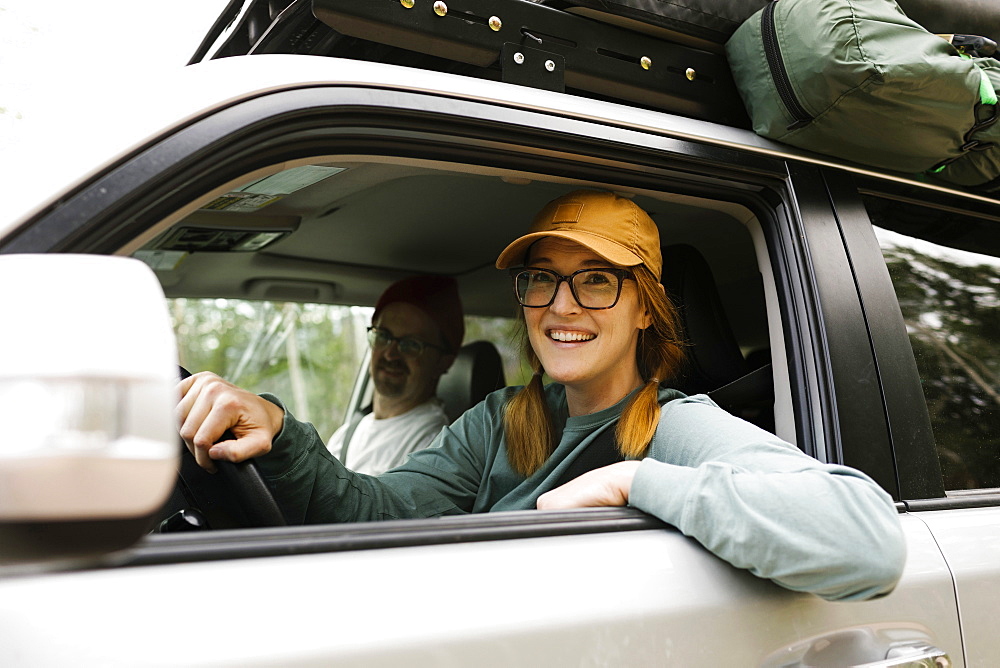 Woman and man sitting in off road car with tent on roof