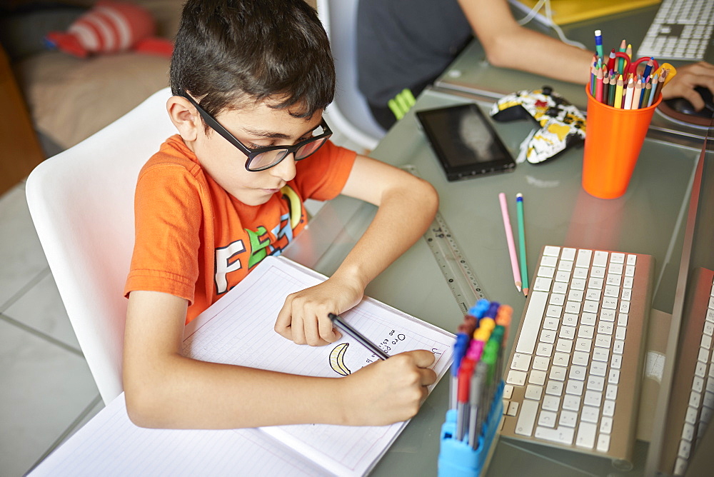 Two boys (8-9, 14-15) learning at desk at home during Covid-19 lockdown