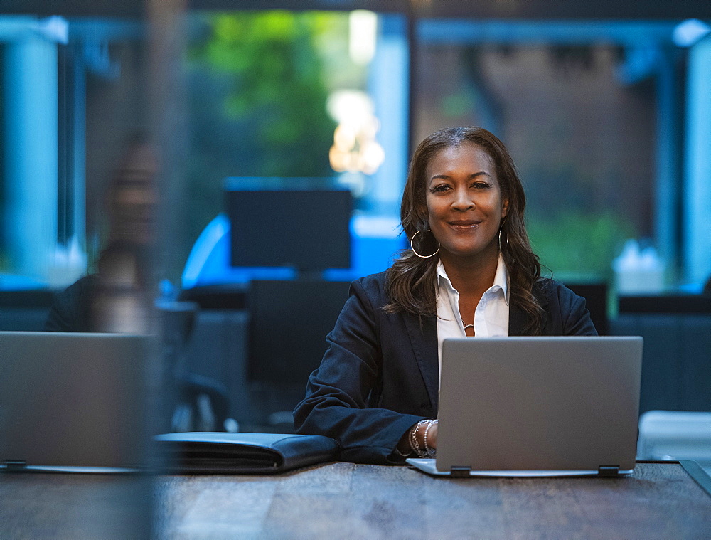 Portrait of smiling businesswoman sitting at desk with laptop in office