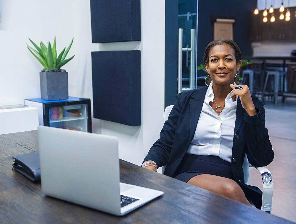 Portrait of smiling businesswoman sitting at desk in office