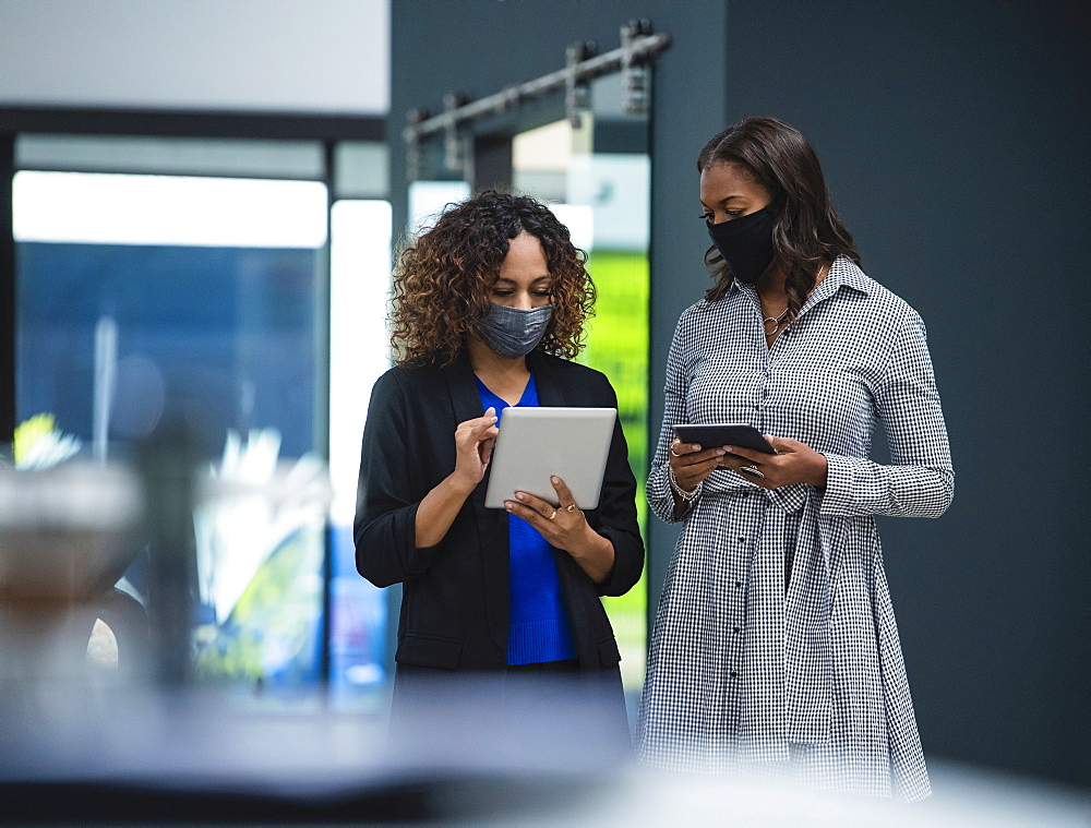 Businesswomen in face masks using digital tablets in office