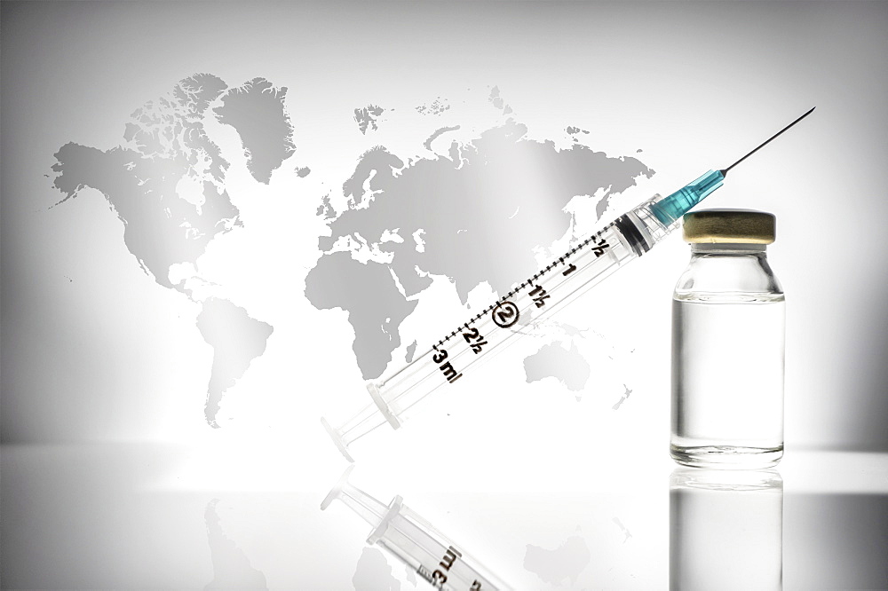 Studio shot of laboratory vial and syringe with world map in background