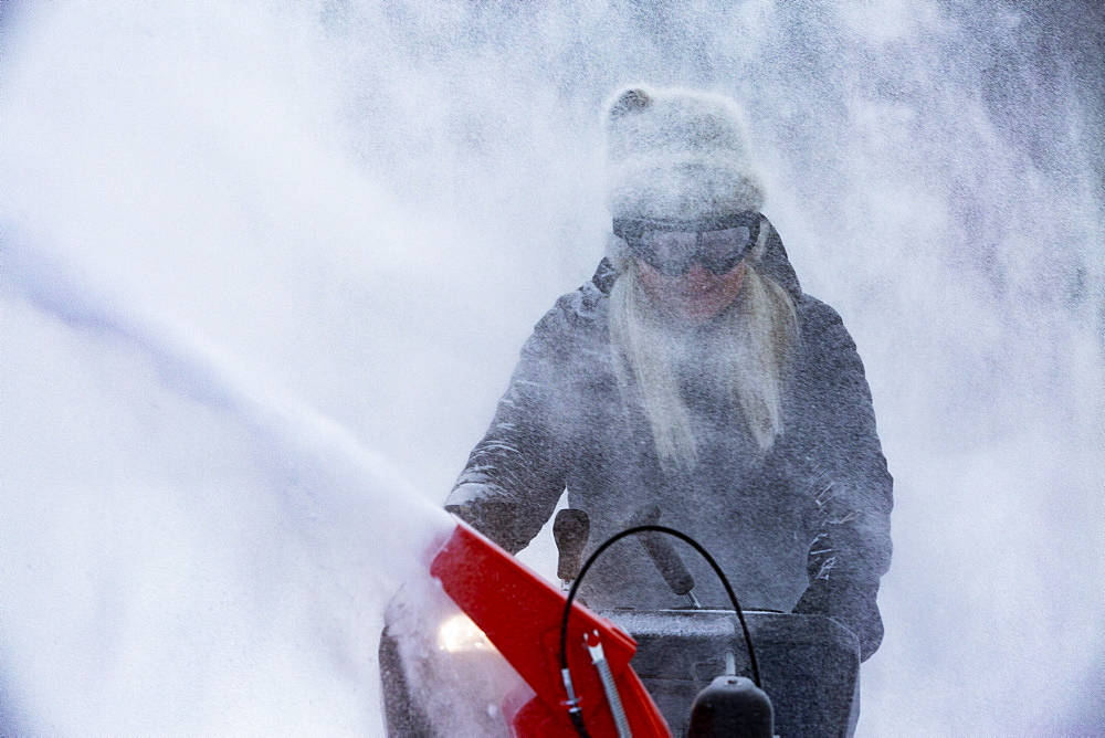 Senior woman clearing snow using snowblower