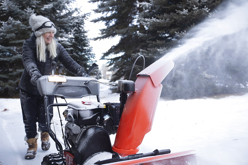 USA, Idaho, Bellevue, Senior woman clearing snow using snowblower