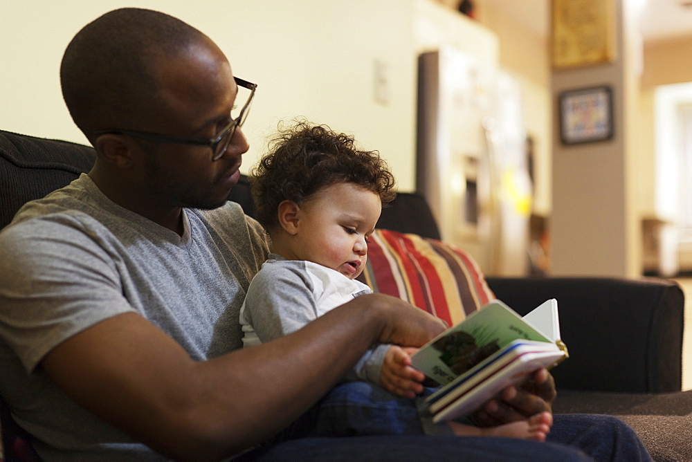 Father reading to baby on sofa