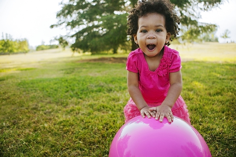 Black girl playing with ball in grass