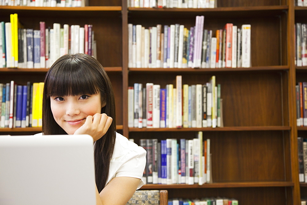 Asian woman using laptop in library